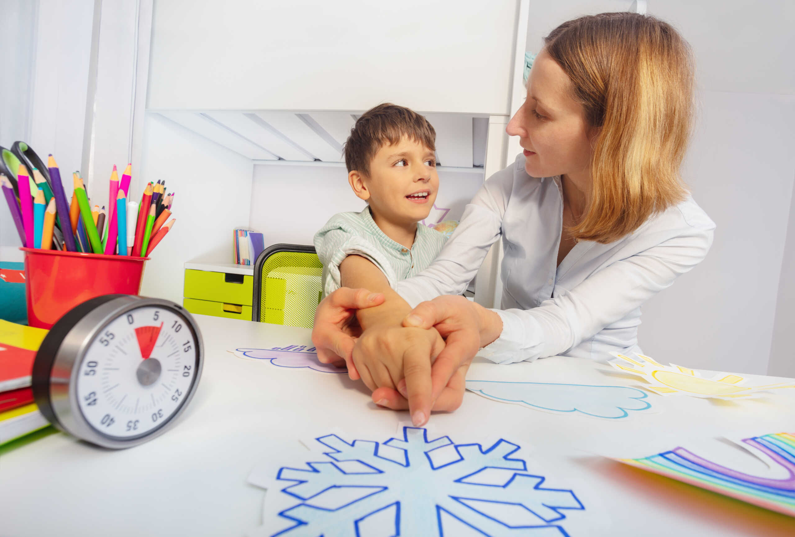 Boy with autism spectrum disorder learn weather using cards, teacher hold hands and point to correct one