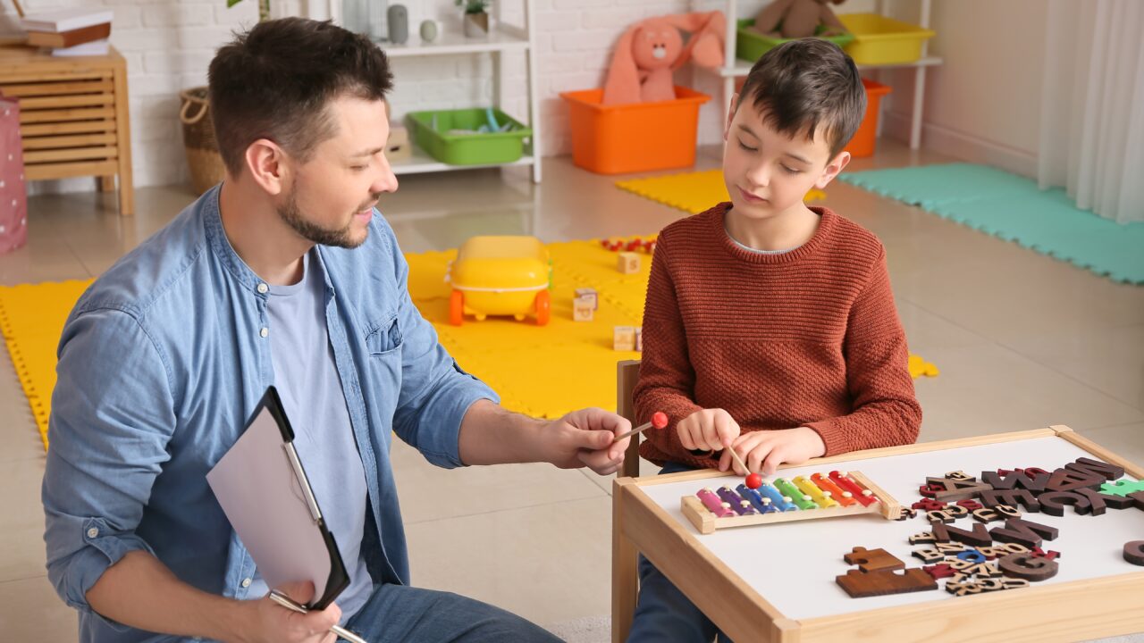 Male,Psychologist,Working,With,Little,Boy,In,Office.,Autism,Concept